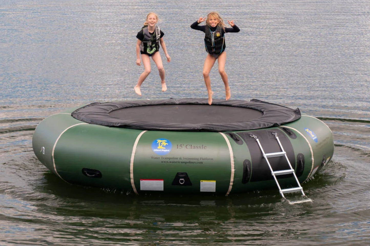 Family on Island Hopper 15ft Classic natural green steel frame water trampoline anchored on a summer lake