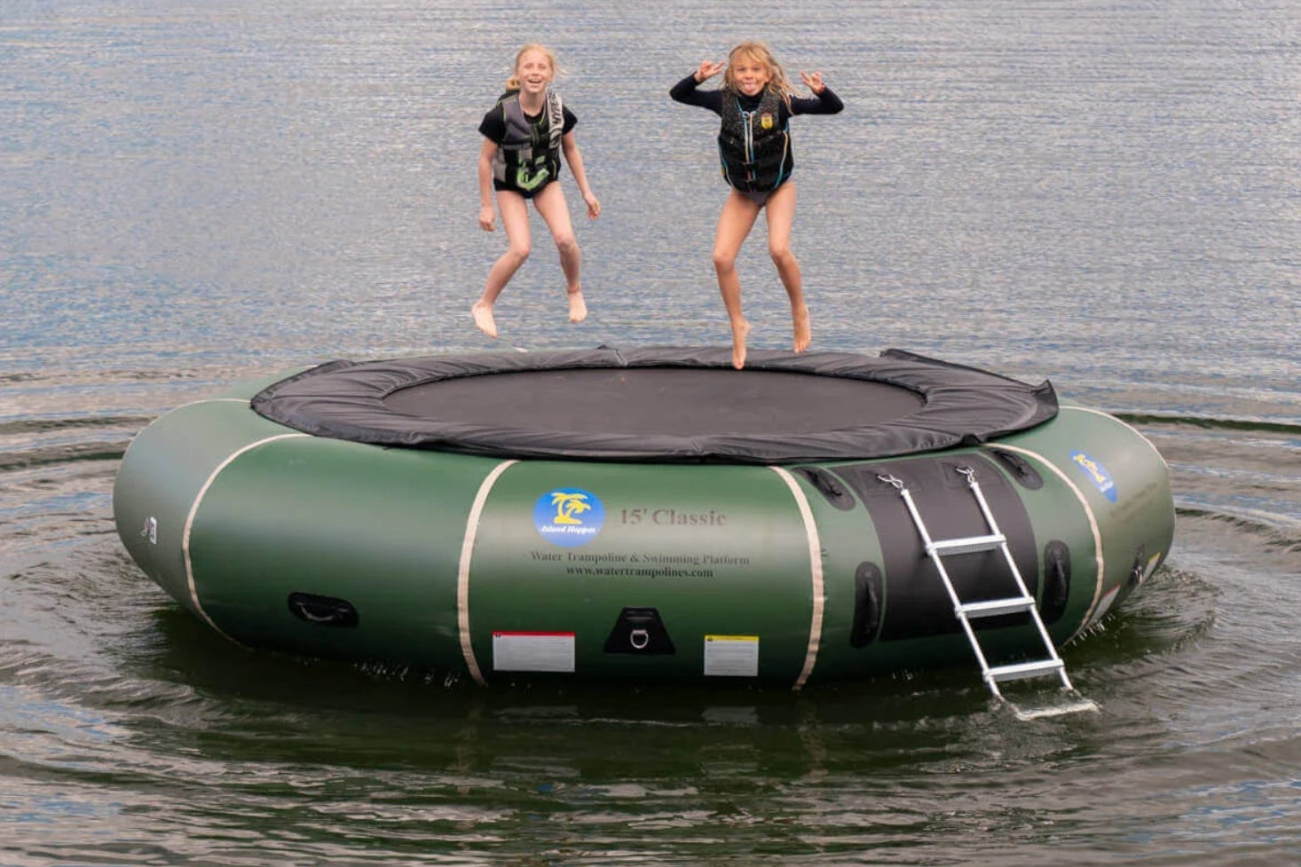 Family on Island Hopper 15ft Classic natural green steel frame water trampoline anchored on a summer lake